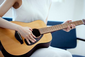 ソファーでギターを弾く日本人女性