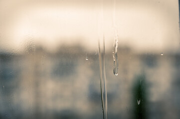 A jet of water on a dirty window pane. Blurred and unfocused background. Selective focus.