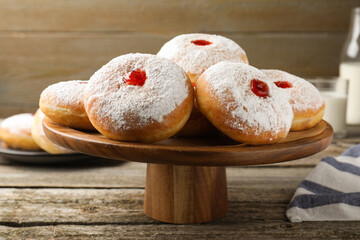 Pastry stand with delicious jelly donuts on wooden table