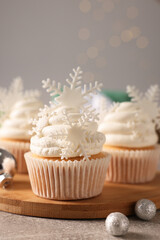 Tasty Christmas cupcakes with snowflakes on grey table