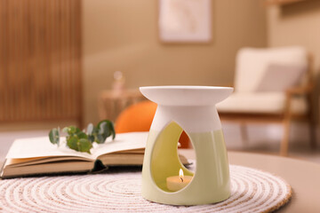 Stylish aroma lamp with small candle on table indoors