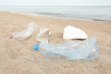 Garbage scattered on beach near sea, closeup. Recycling problem