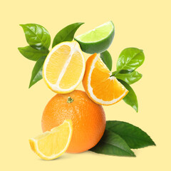 Fresh juicy citrus fruits and green leaves on beige background