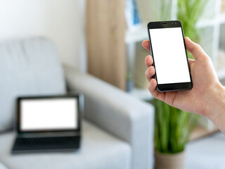 Online information. Digital mockup. Mobile connection. Unrecognizable man holding smartphone with blank screen in hands light room interior blur.