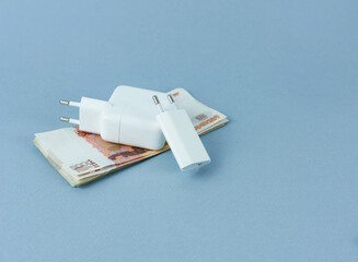 Phone and tablet chargers lie on a stack of bills.  