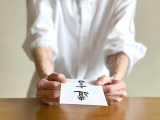 遺言文字入り封筒を差し出す高齢女性の手