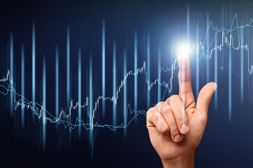 Obraz premium Hand pointing at business chart on blue background. Stock, market and trade concept.