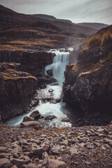Fototapeta premium Beutiful fossardalur waterfall in iceland with beautiful scenery around. Cloudy weather but still very nice to see.