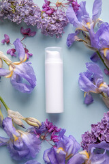Obraz na płótnie Canvas Mockup for a cosmetic brand on a purple background, surrounded by flowers. Set of white jars of cosmetics for skin care. Concept of eco-friendly products in glamor style. Cream packaging