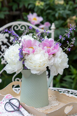 Blumenstrauß mit Pfingstrosen und Katzenminze in vintage Vase im Garten