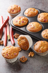 Freshly baked muffins with rhubarb and walnuts close-up in a baking dish on the table. Vertical