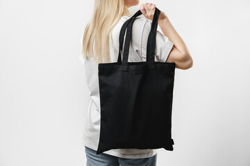 Female holding black cotton bag in her hands on white background