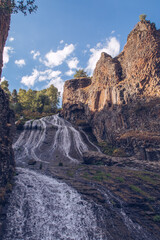 Fototapeta na wymiar Jermuk waterfall flowing stream picturesque view among the canyon rocks sunlit gorge. Armenian stock photography