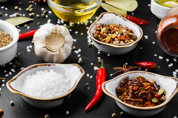 Olive oil, herbs and spices on black background