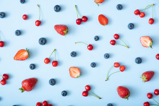 Pattern with strawberries, cherries and raspberries on a blue background