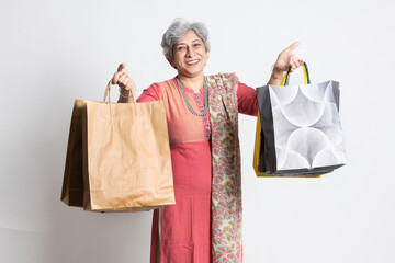 Happy excited indian senior mature woman holding shopping bags. elderly female shopper wearing...
