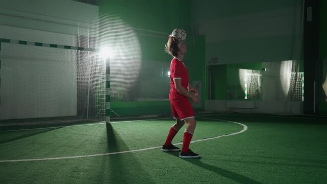 Professional football player performs tricks with a soccer ball, balances the ball on her head, cinematic light, 4k slow motion.