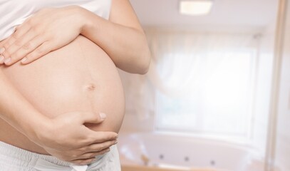 A young pregnant woman touching her belly and caring about her health