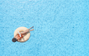 Fototapeta na wymiar woman floating in swimming pool and reading book