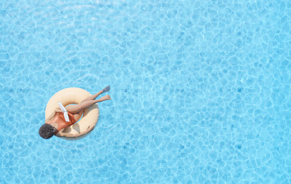 woman floating in swimming pool and reading book