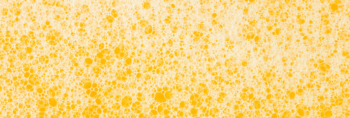 Texture of white foam on a yellow background. Cleansing mousse for the face or shaving foam or...