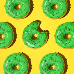 Pattern of green donuts on a yellow background. Square, studio photo.