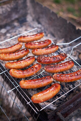 Tasty Sausages grilling on charcoal grill grate