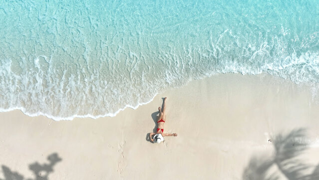 Aerial view of woman body in bikini sunbathing as laying on the  beach, blue sea water in background -Summer fashion concept
