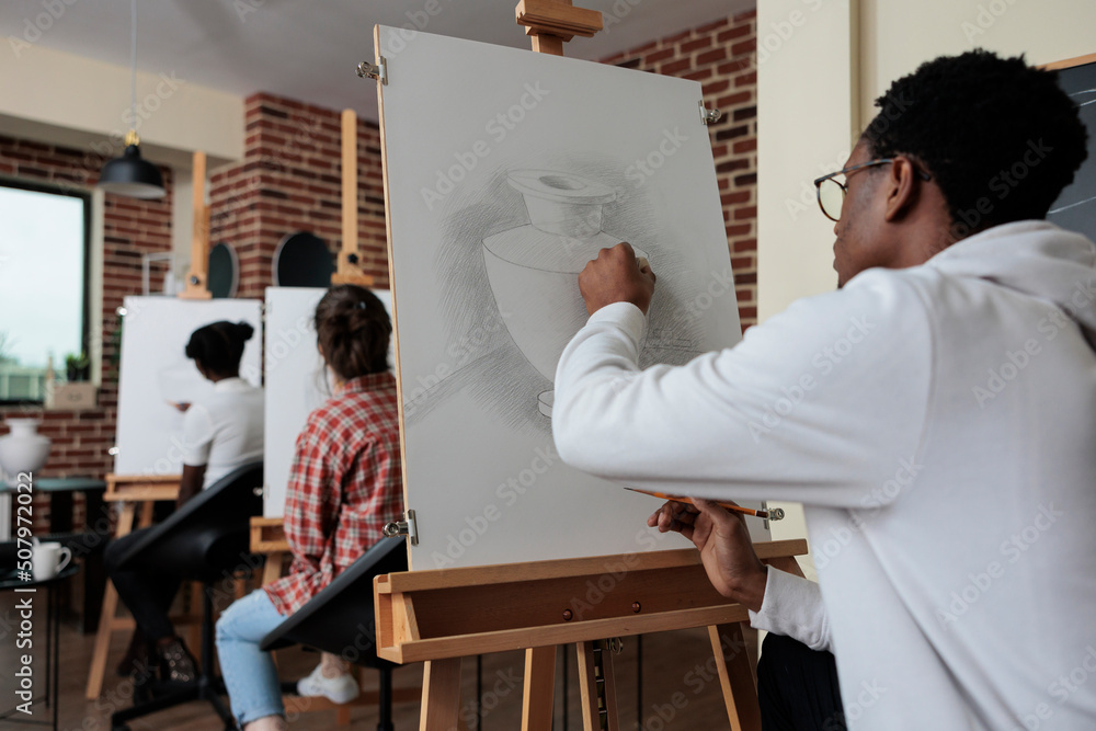 Poster young painter sitting in front of white canvas drawing vase model using graphic pencil working at sk