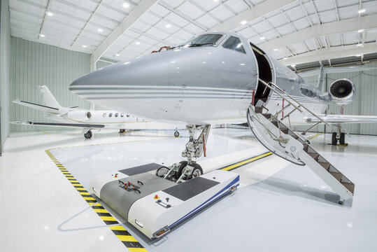 Two small private Jet airplanes parked in a hangar - stock photo
