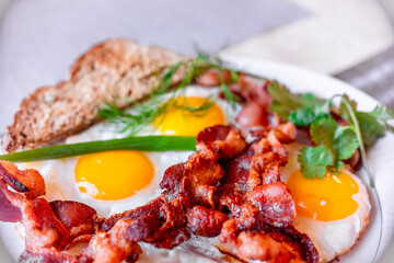 Tasty fried eggs eggs and crispy bacon, close-up, great classic breakfast. Macro photography, shallow depth of field.