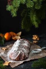 Christmas stollen on a dark background. Traditional German Christmas dessert. Cake with nuts, raisins, marzipan and dried fruits on a newspaper. Baking for Christmas