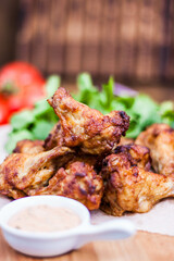 Spicy Homemade Buffalo wings with sauce, beer, tomatoes and herbs on a wooden board. Restaurant serving.