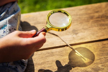 little boy kindles a fire with the help of the sun and a magnifying glass