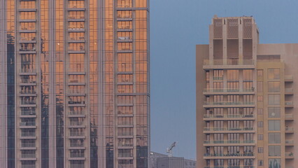 Skyscrapers with stunning sun reflections on the teal and orange glass facades, with blue sky timelapse
