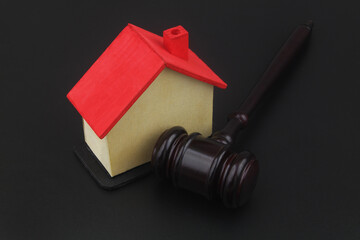 Real estate laws and auction concept. Wooden judge gavel and house model on black background.	