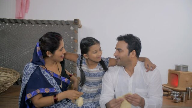 Indian village parents happily embracing their cute daughter - parenting  nuclear family in Indian village  village parents . Village scene of a beautiful young girl smiling while hugging her paren...