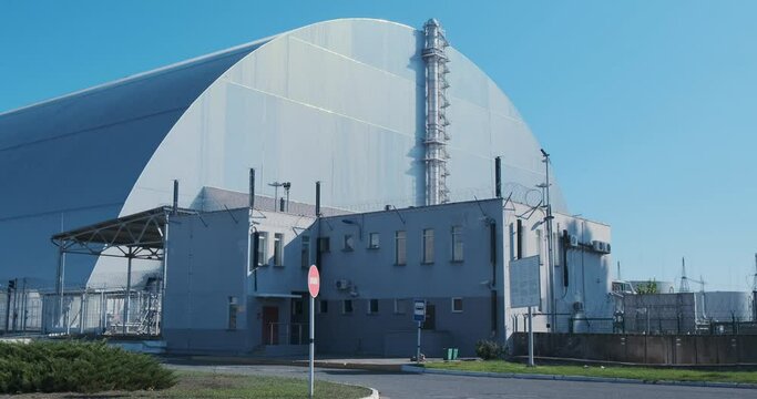 Sarcophagus over the destroyed reactor of the Chernobyl nuclear power plant. Giant metal hangar, radiation protection. No people, windy weather.