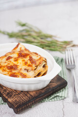 Close-up of casserole with potatoes, cheese, chicken on the kitchen table on a wooden board. Homemade rustic casserole. Healthy cuisine.