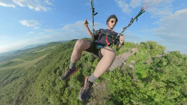 Man flying the paragliding over the mountains at sunny day, adventure concept