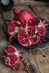 Fototapeta na wymiar beautiful pomegranate fruits with pits on a metal plate on a wooden table in a dark key in rustic style
