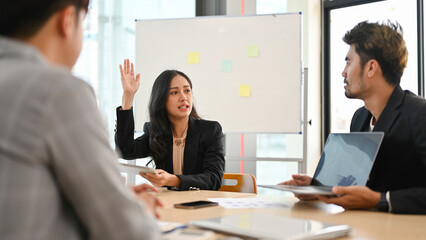 Confident Asian businesswoman raise her hand to share her ideas in the meeting