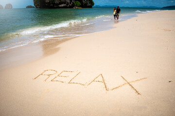 Fotografía conceptual. Mensaje de "relájate" escrito en arena de playa hermosa.. Viajes y turismo