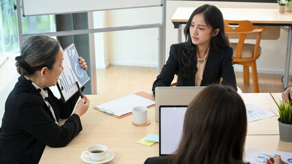 Young business worker in the meeting, intently listening her aged female boss
