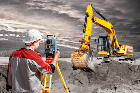 Surveyor engineer is measuring level on construction site. Surveyors ensure precise measurements before undertaking large construction projects. Excavator on the background of the sunset sky.