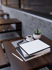 Digital tablet mockup on modern outdoor wood table. Outdoor coffee shop seating area.
