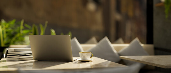 Laptop computer and accessories on a modern marble table over the luxury restaurant sofa