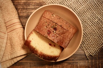 fruitcake slices in a bowl cup isolated on a wooden backdrop with burlap or cloths aside.