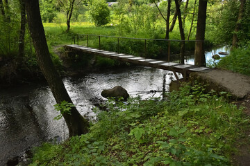 Bridge over a small forest river with green, beautiful banks, in spring