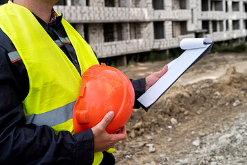young strong workers in special uniforms compare construction work with the plan on paper.